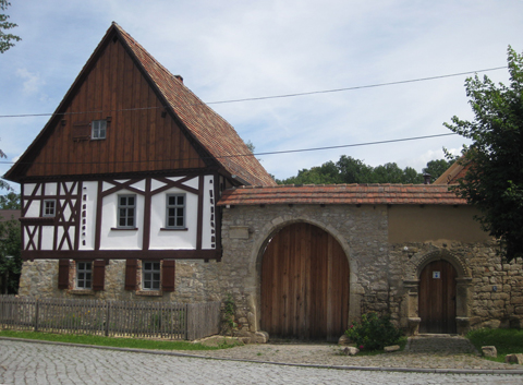 Haus aus Bruchsteinen und Fachwerk mit Bruchsteinmauer und großem hölzernen Hoftor
